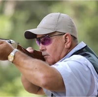 a man wearing sunglasses and a hat is shooting a gun